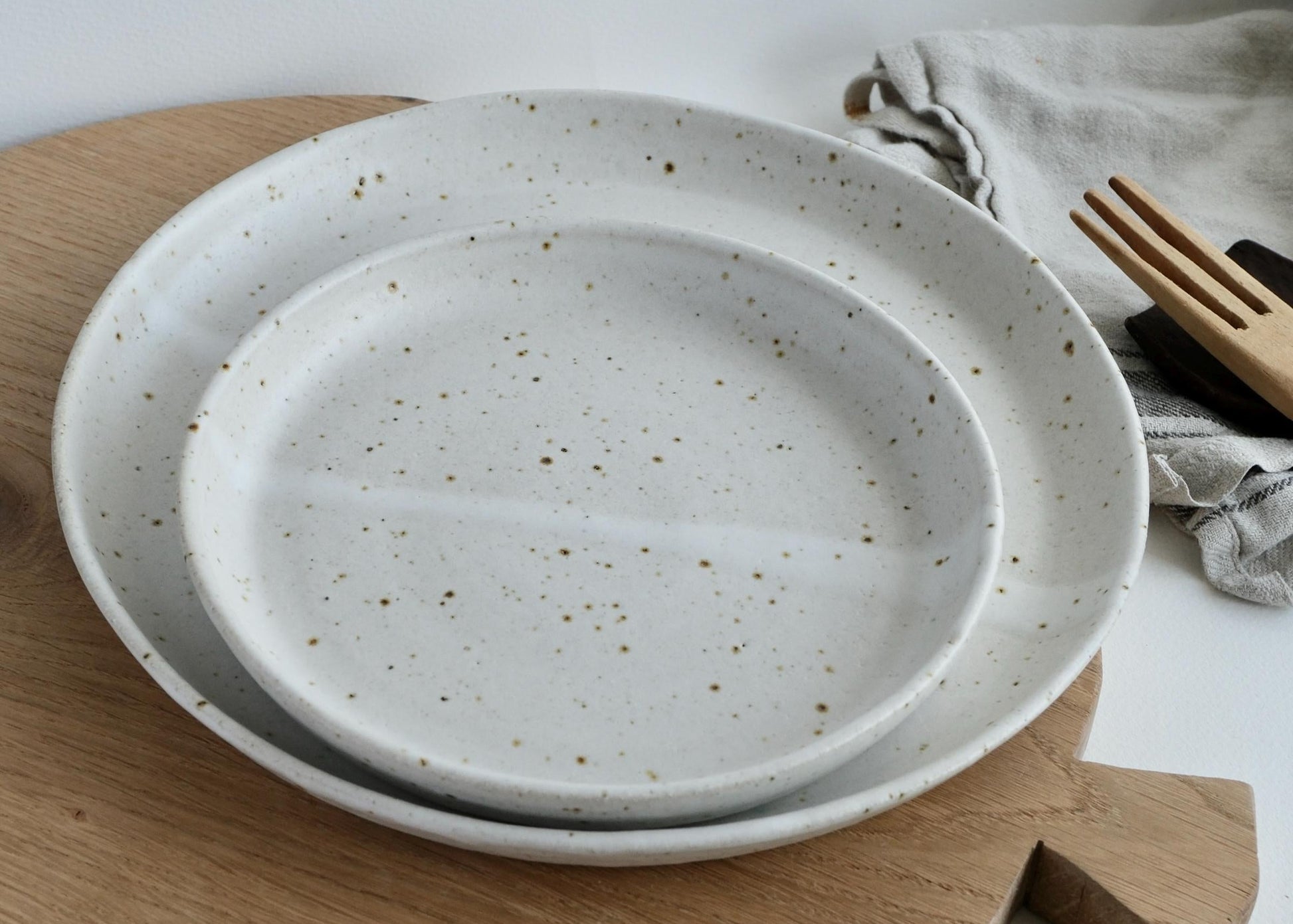 Speckled ceramic small side plates on a wooden board with a neutral background