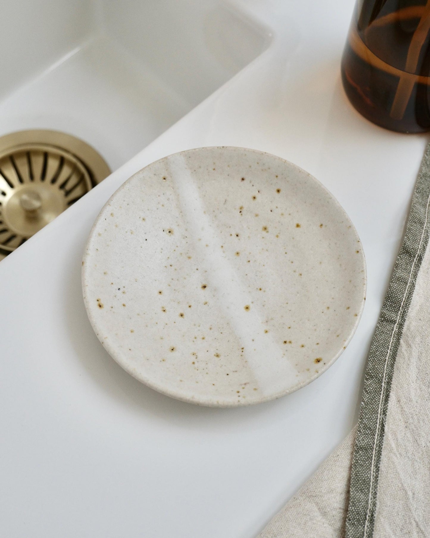 overhead view of a white Speckled ceramic dish on a kitchen counter with a sink in the background